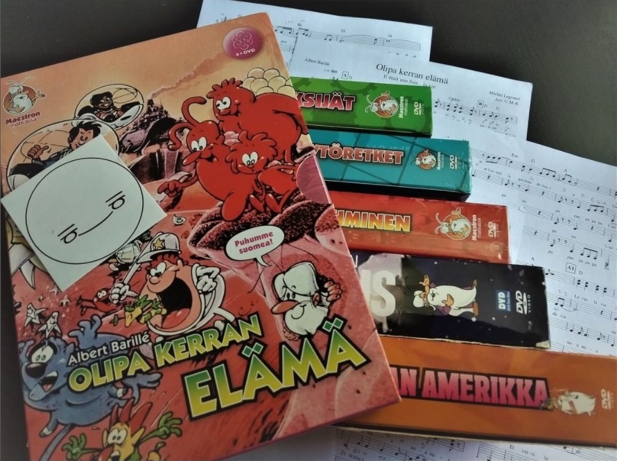 Olipa kerran -sarjan DVD-koteloita sekä osittain näkyvä nuottisivu.